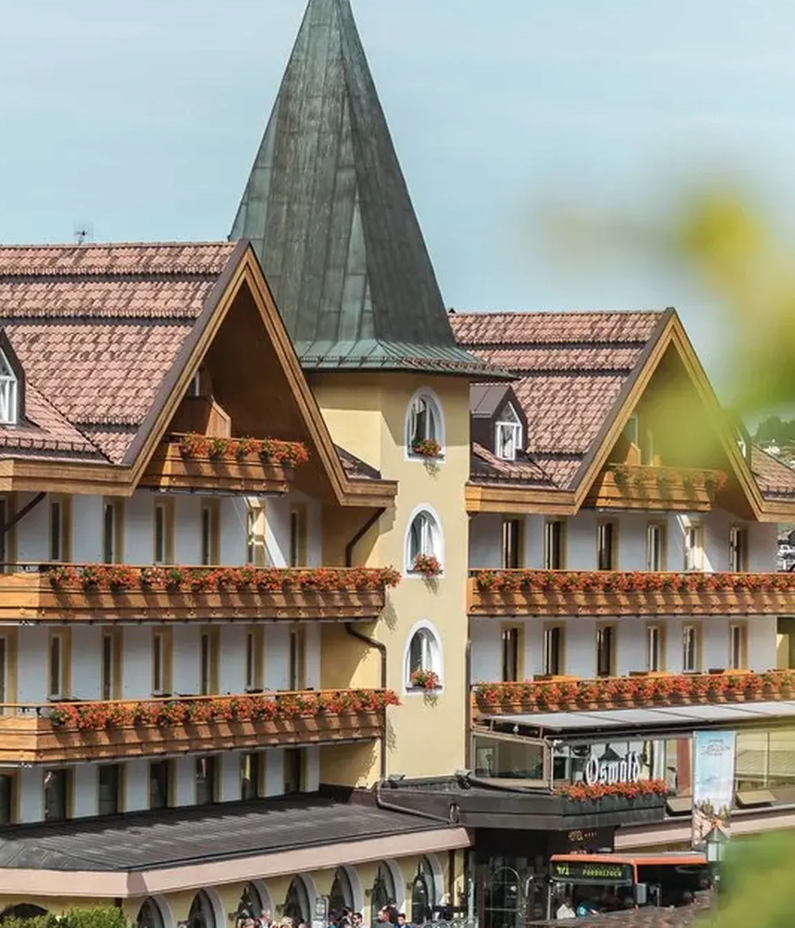 Exterior view of Hotel Oswald before renovation and expansion, highlighting its iconic yellow turret and main white building.