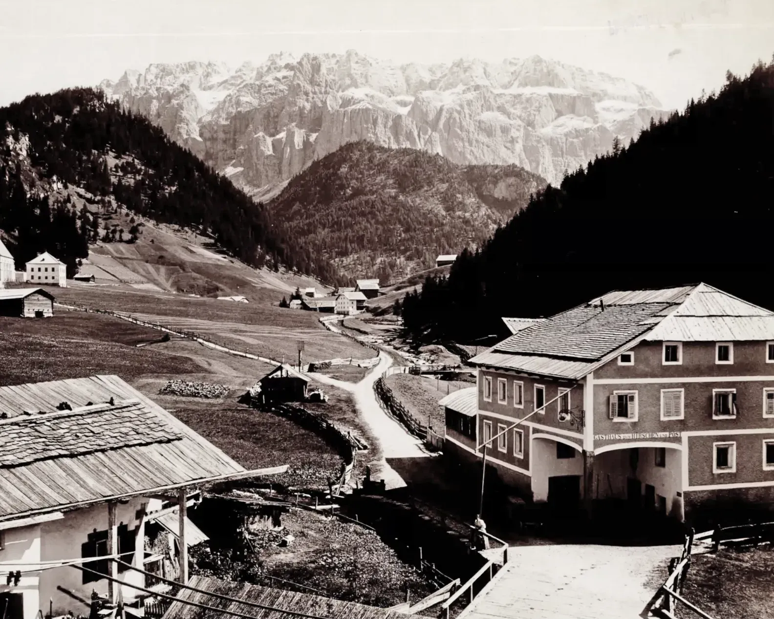 Historical photo of Selva di Val Gardena at the end of the 19th century, featuring traditional buildings and the surrounding mountain lands
