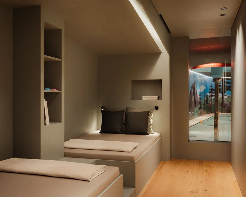 Interno moderno e minimalista con sedute integrate e tonalità neutre. Una finestra si affaccia sull’area della piscina interna, creando un’atmosfera serena e raffinata.